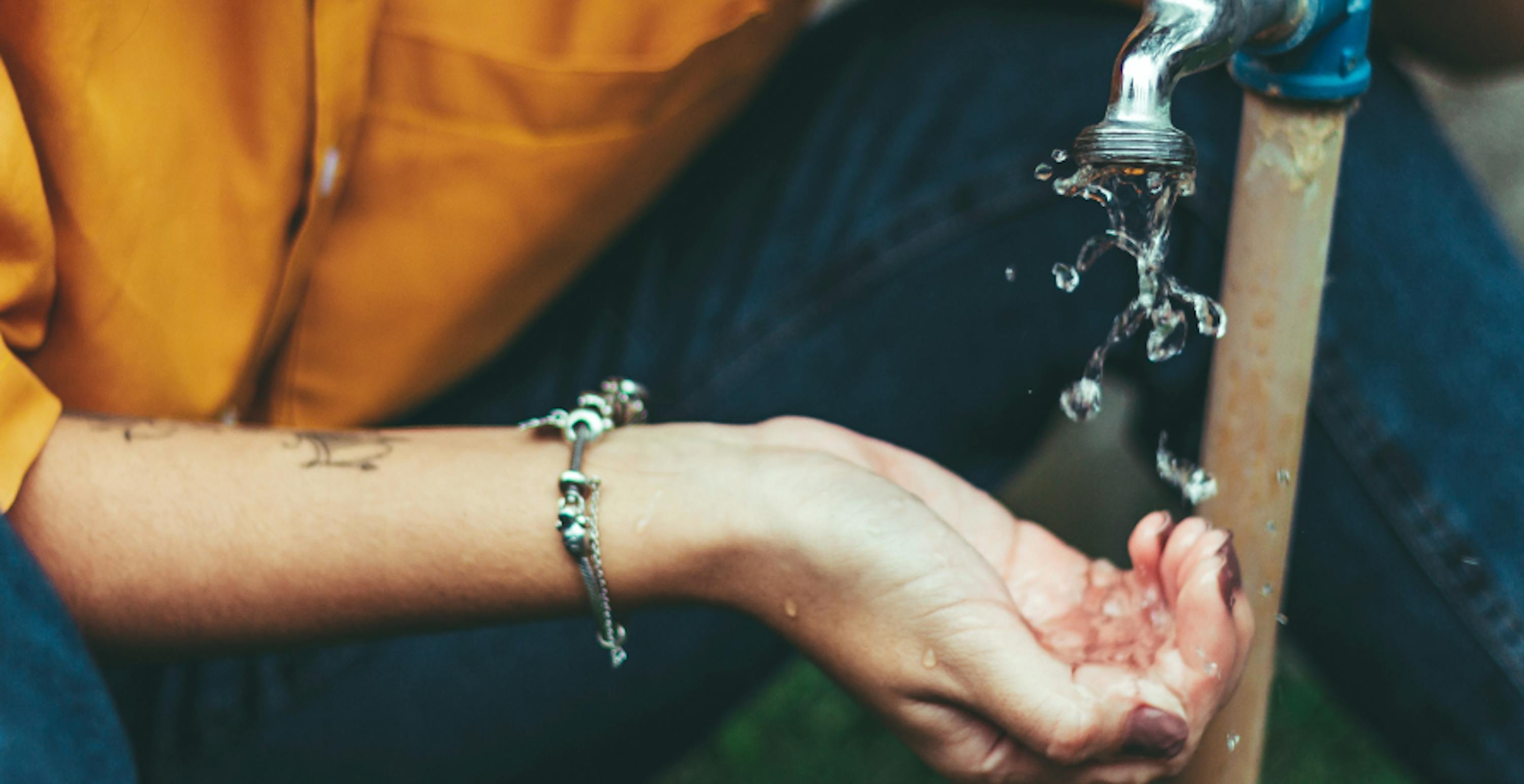 la main d'une femme placée sous un robinet d'eau