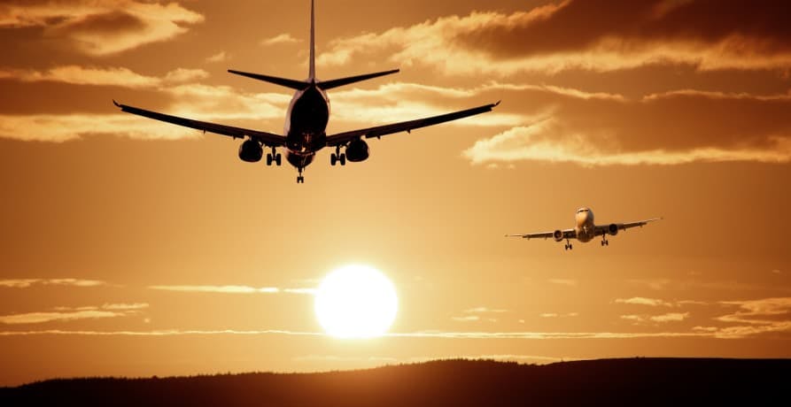 two planes flying in the sky as the sun sets