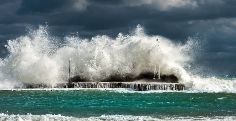 ocean waves crashing on small island with power lines