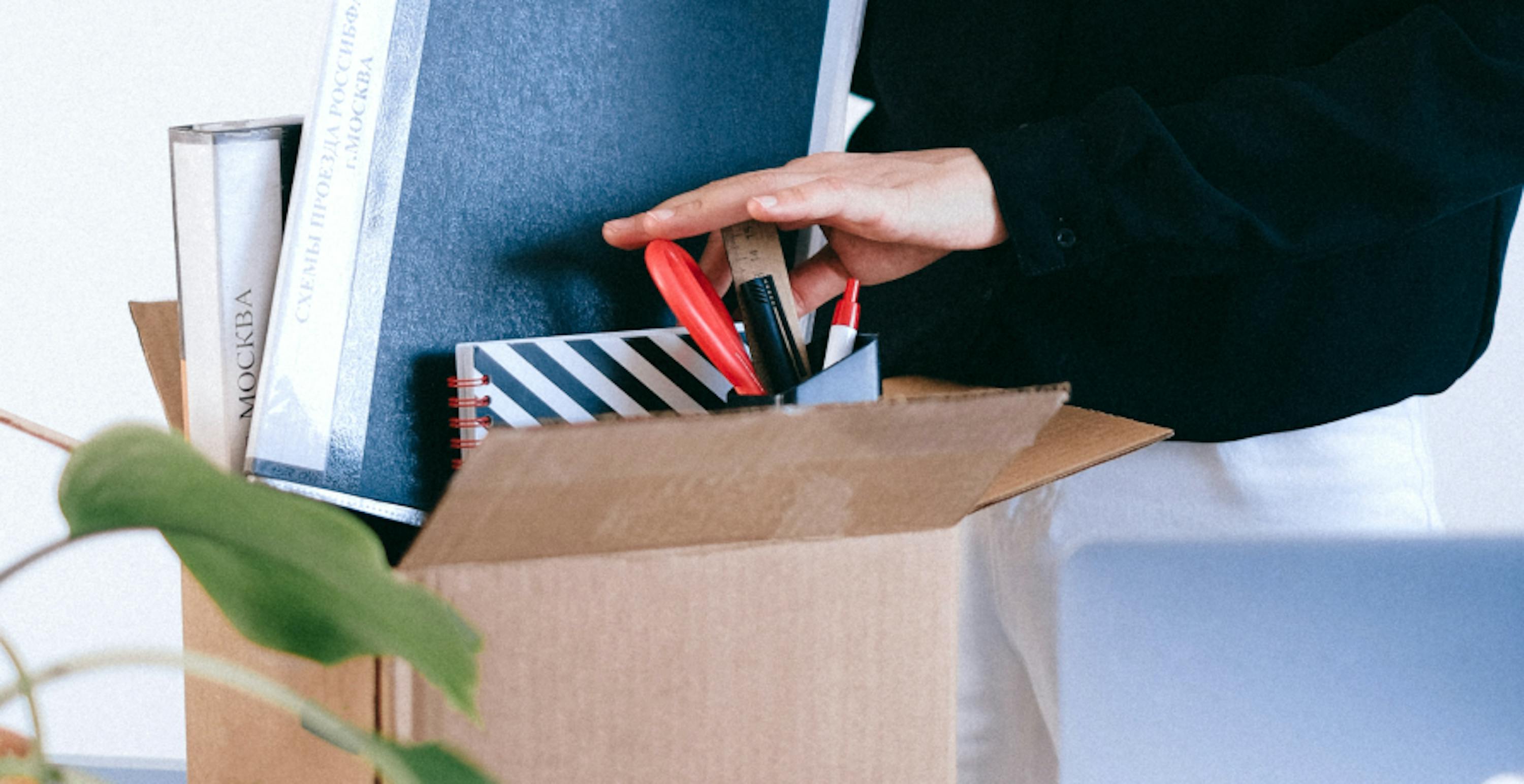 Someone placing belongings into cardboard box