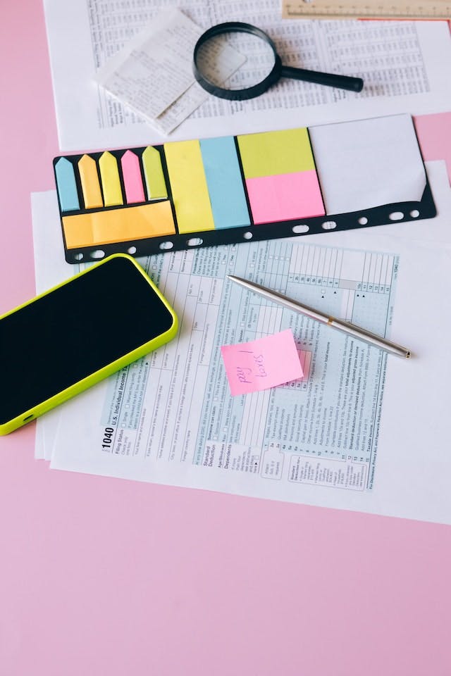 phone, magnifying glass, papers and postit on a table