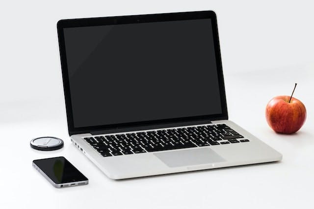 laptop, smartphone and red apple on a white table