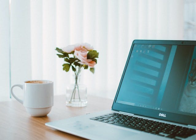 ordinateur portable, café et fleurs sur un bureau