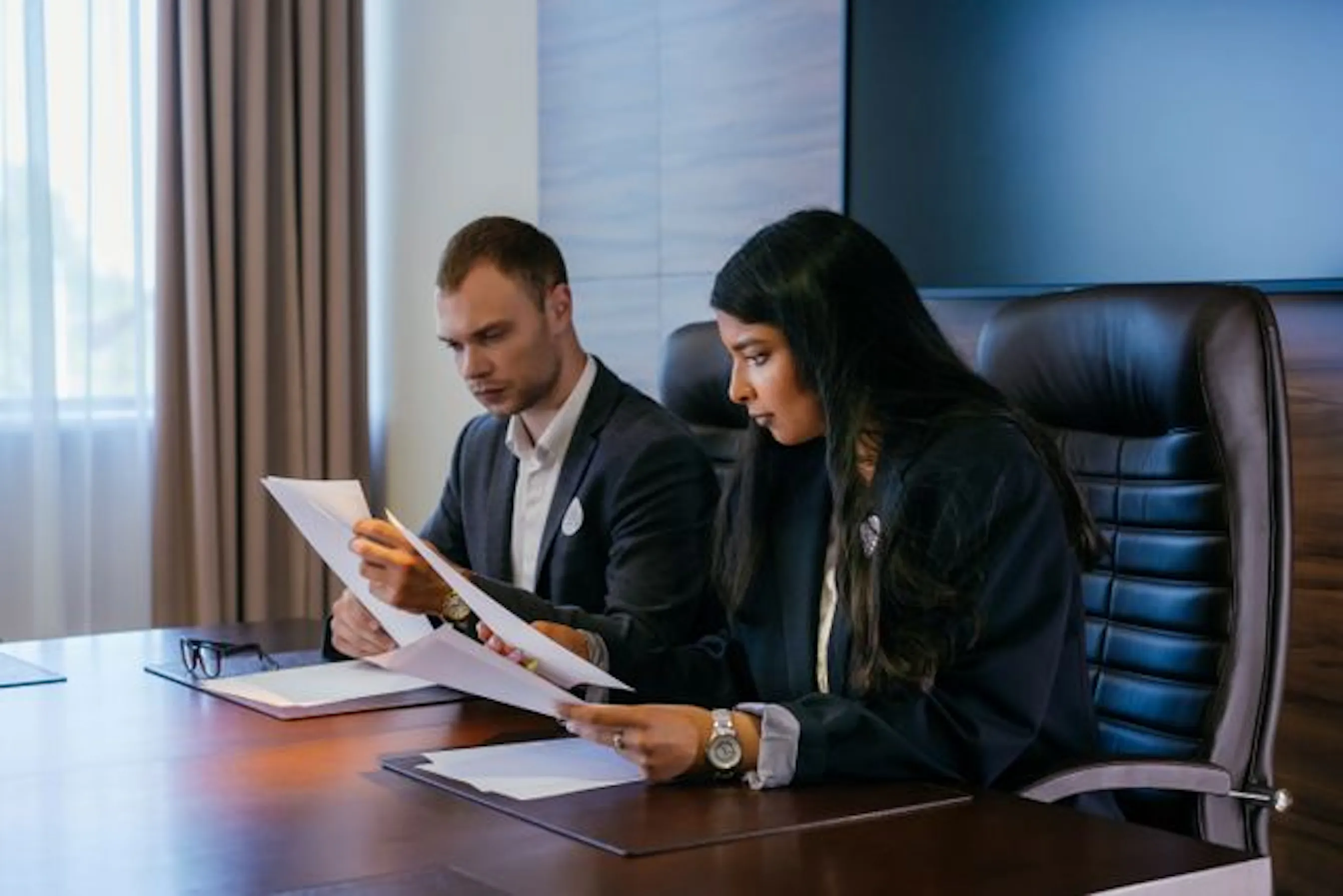 Two colleagues reviewing compliance documents together in an office, representing scope 3 audit and reporting requirements