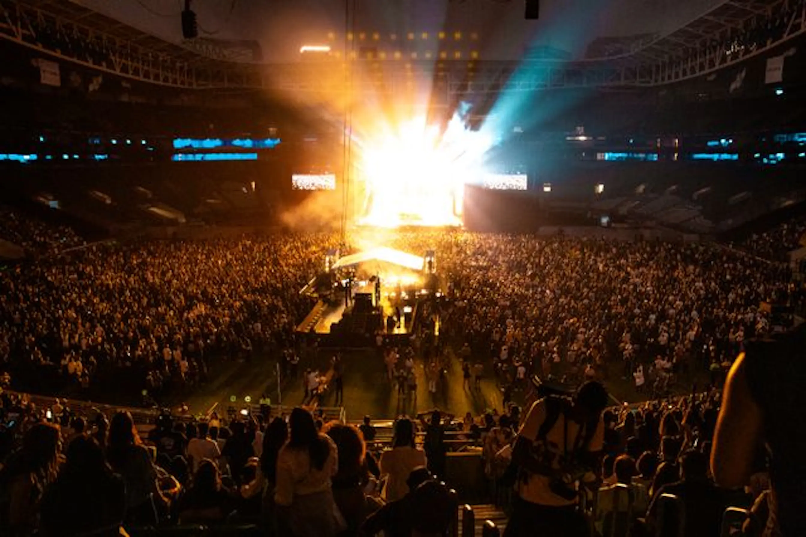 Vue large d'une foule de spectateurs face à une scène de concert illuminée.