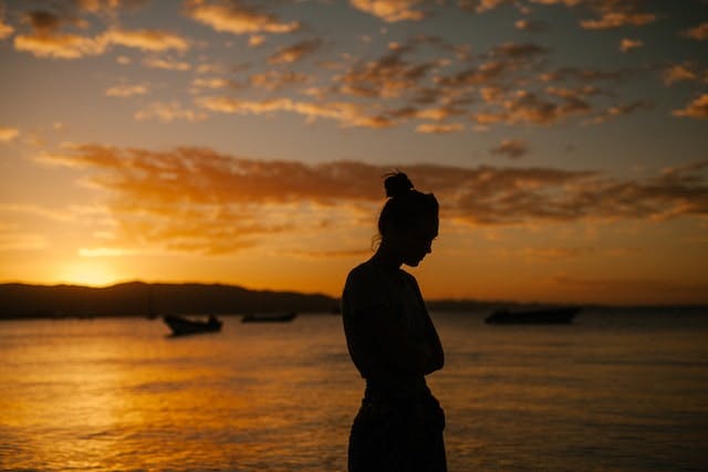 une femme au bord de la mer au coucher du soleil