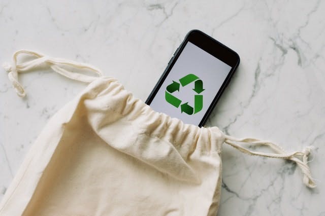 Un sac en tissu et un smartphone avec un logo de recyclage  