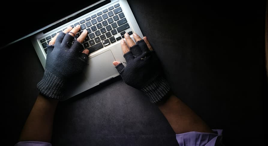 person with gloves on laptop