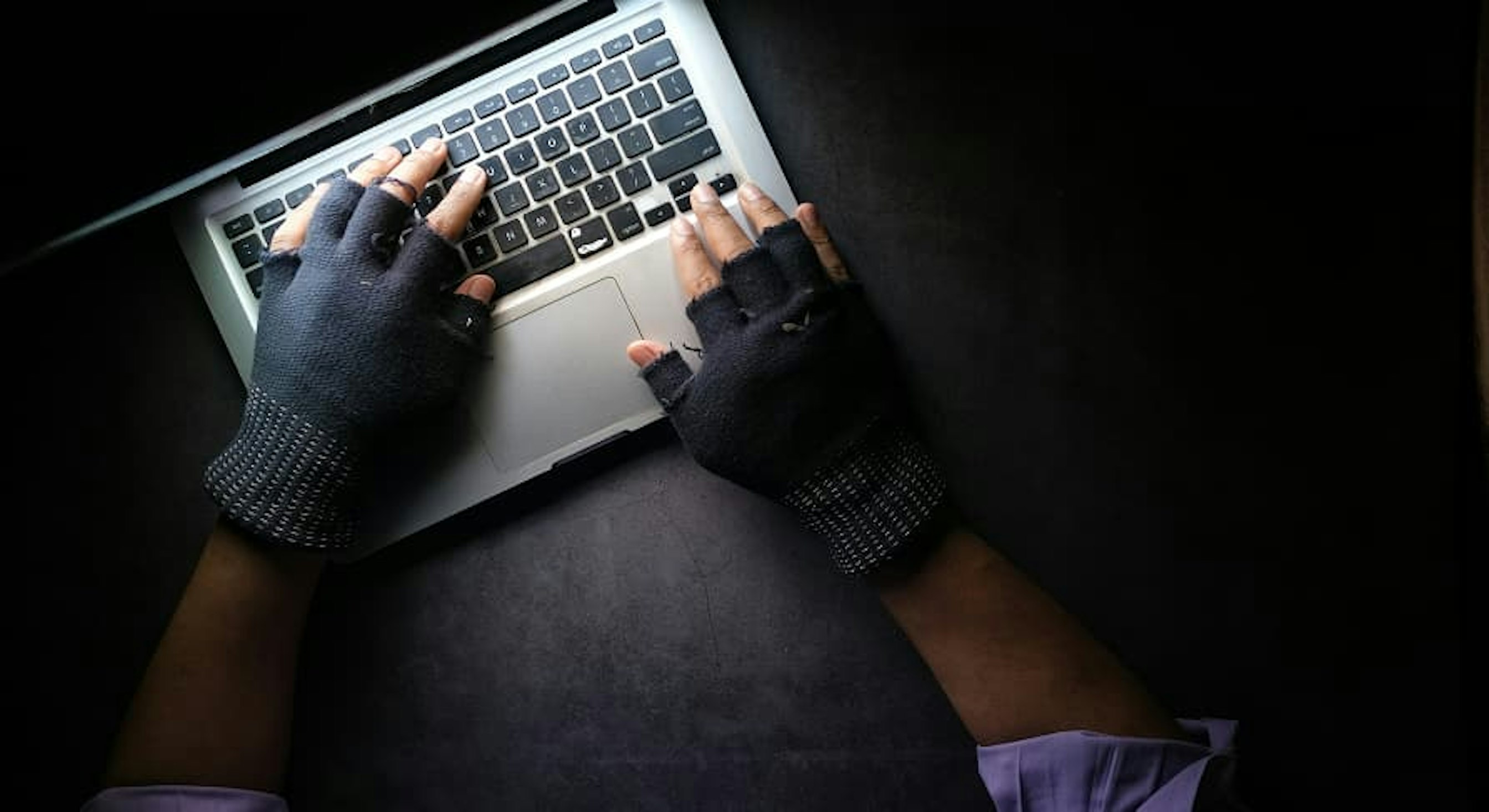 person with gloves on laptop