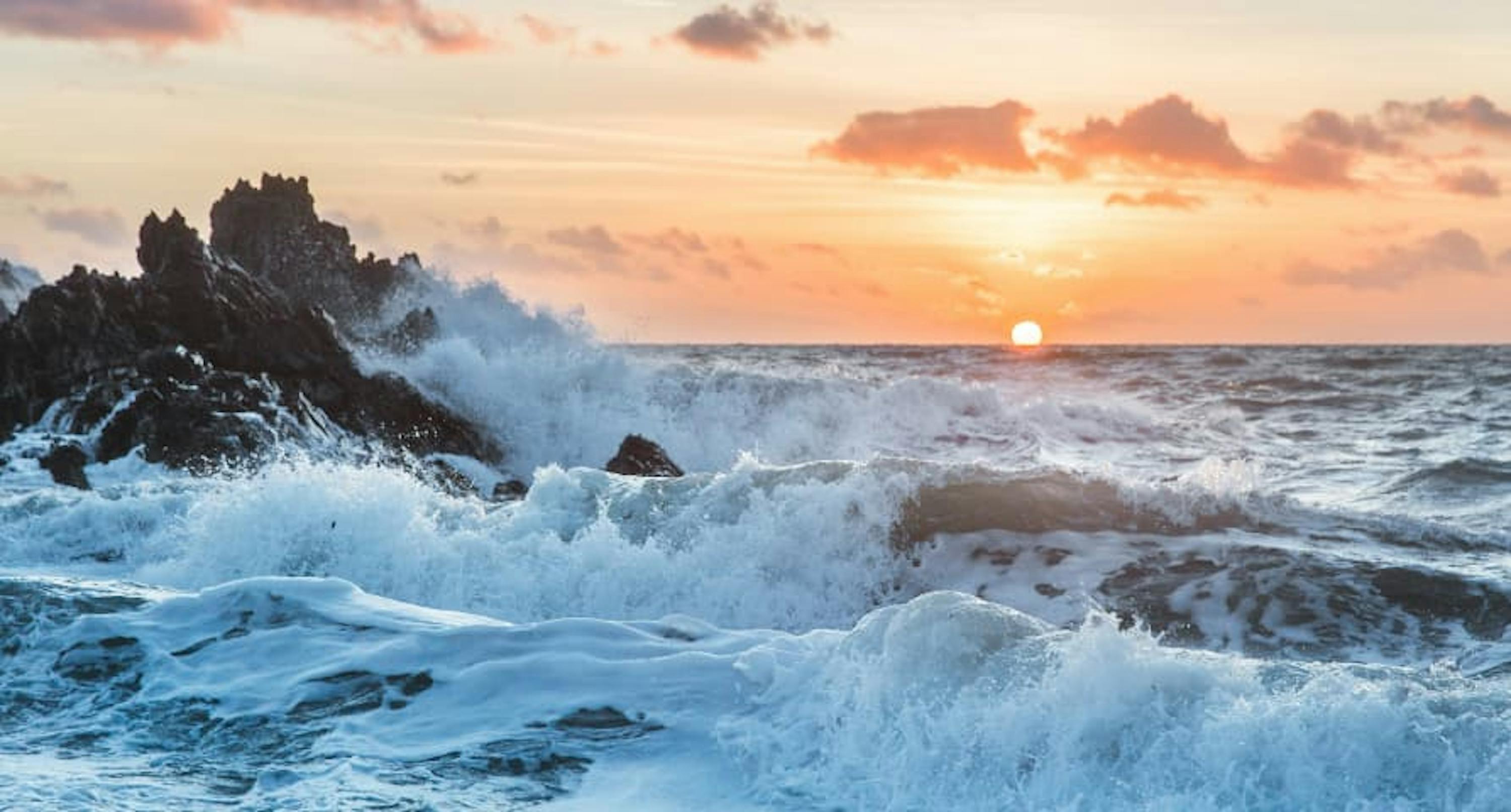 waves crashing on rocks at sunset