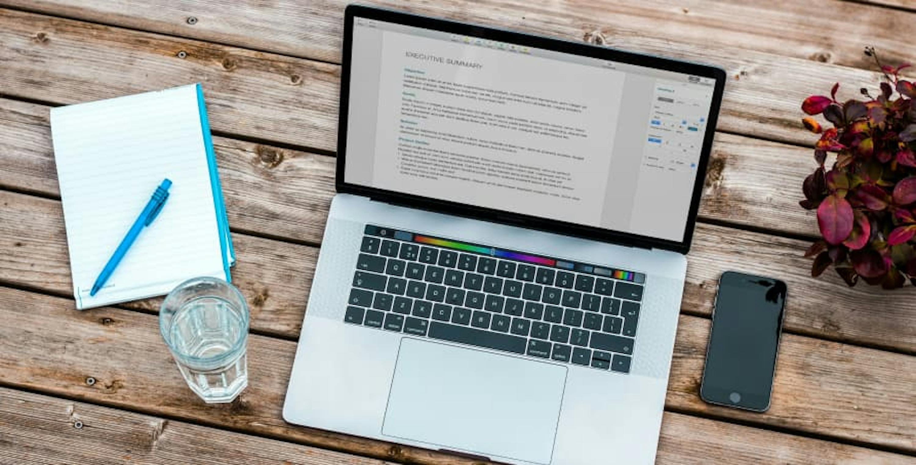 laptop with notepad and glass of water