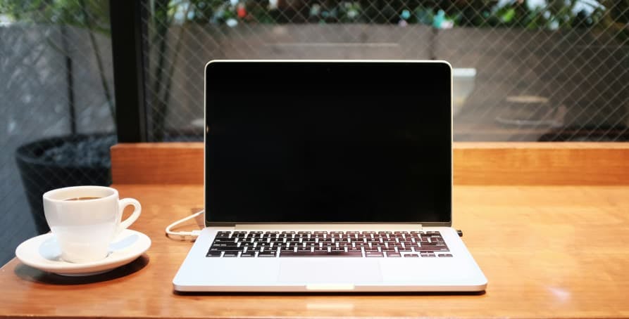 laptop with coffee on light brown desk