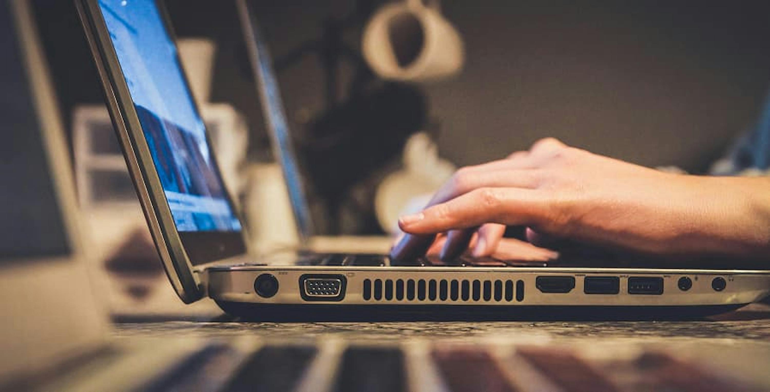 person typing on laptop side view of computer ports