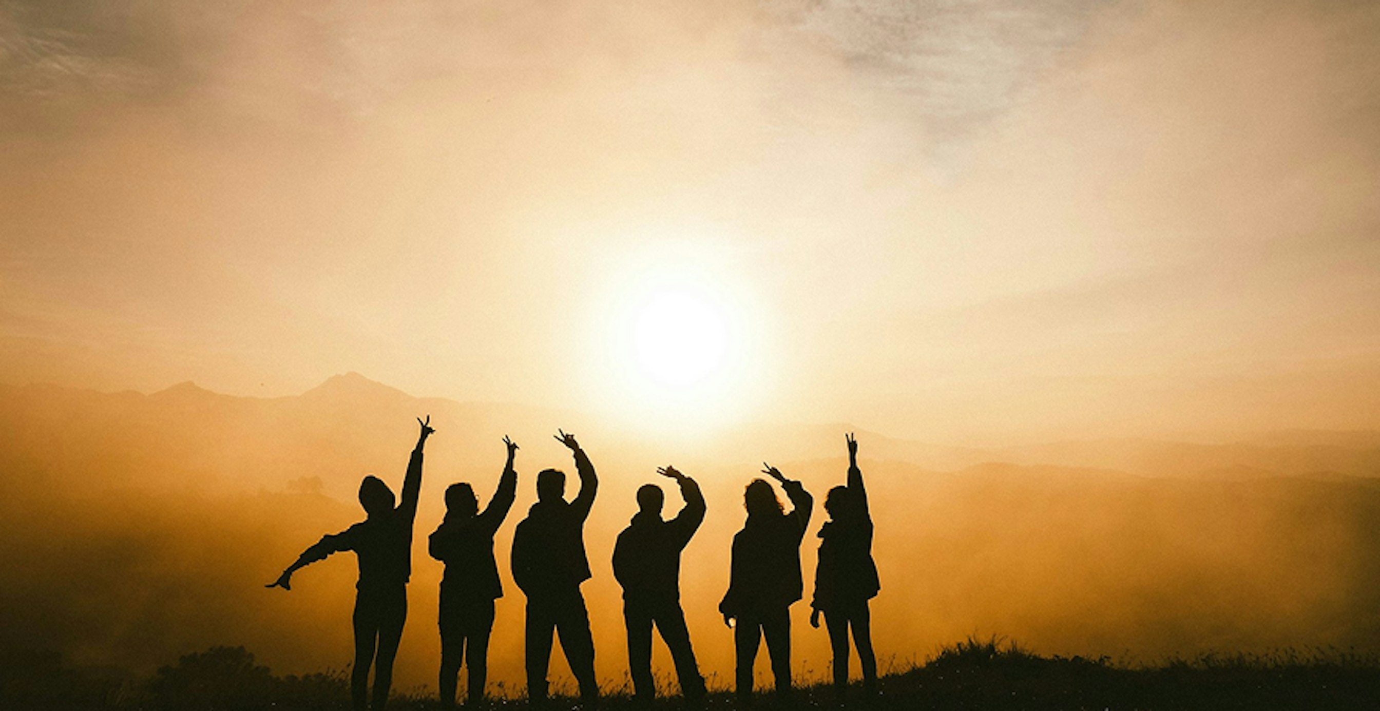 un groupe de personnes devant un coucher de soleil