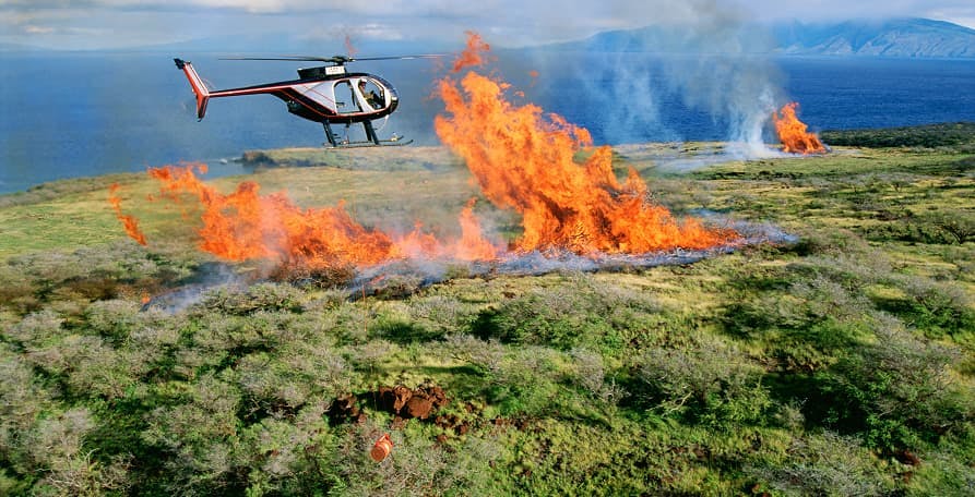 helicopter flying over wildfire