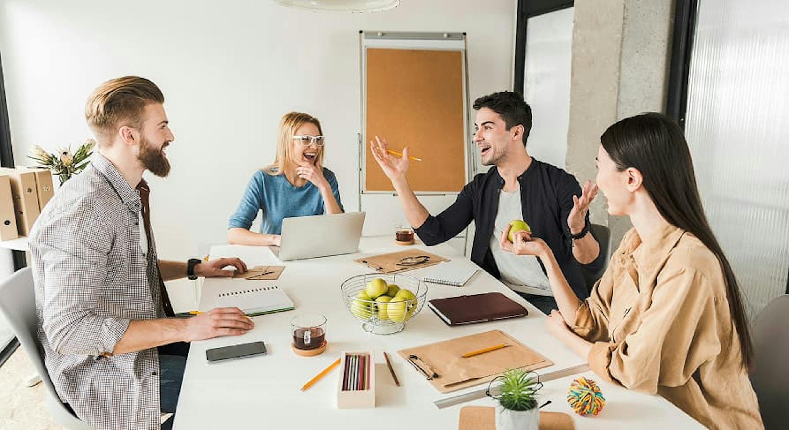 4 smiling employees at office table