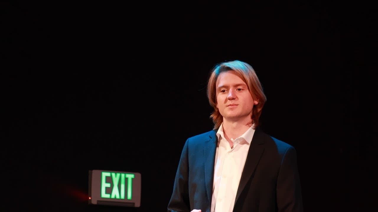 young man in suit long blonde hair green exit sign