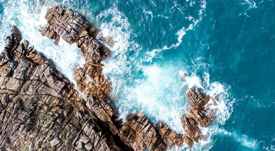 teal water crashing on rigid cliff