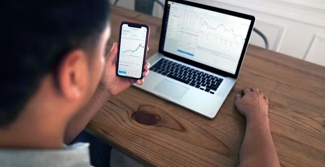 Man looking at smartphone and laptop