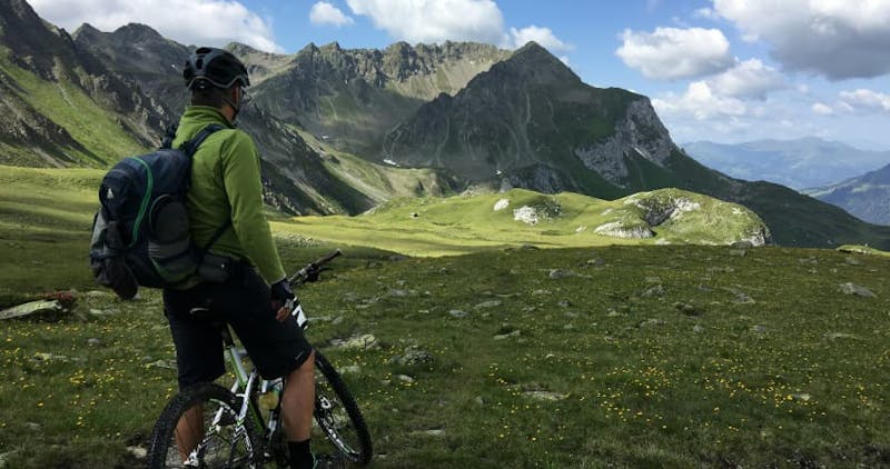 person biking overlooking mountain and green lush