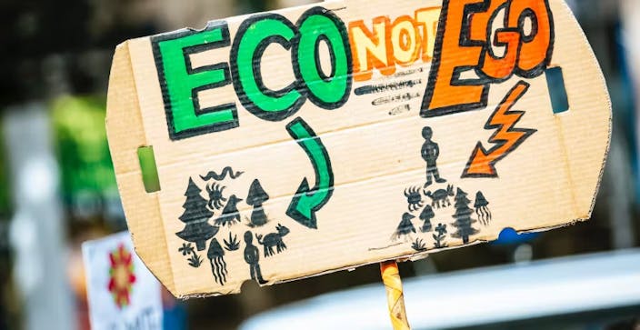 protester's sign : "eco not ego"
