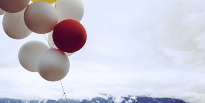 white and red balloons floating with mountain scapes behind