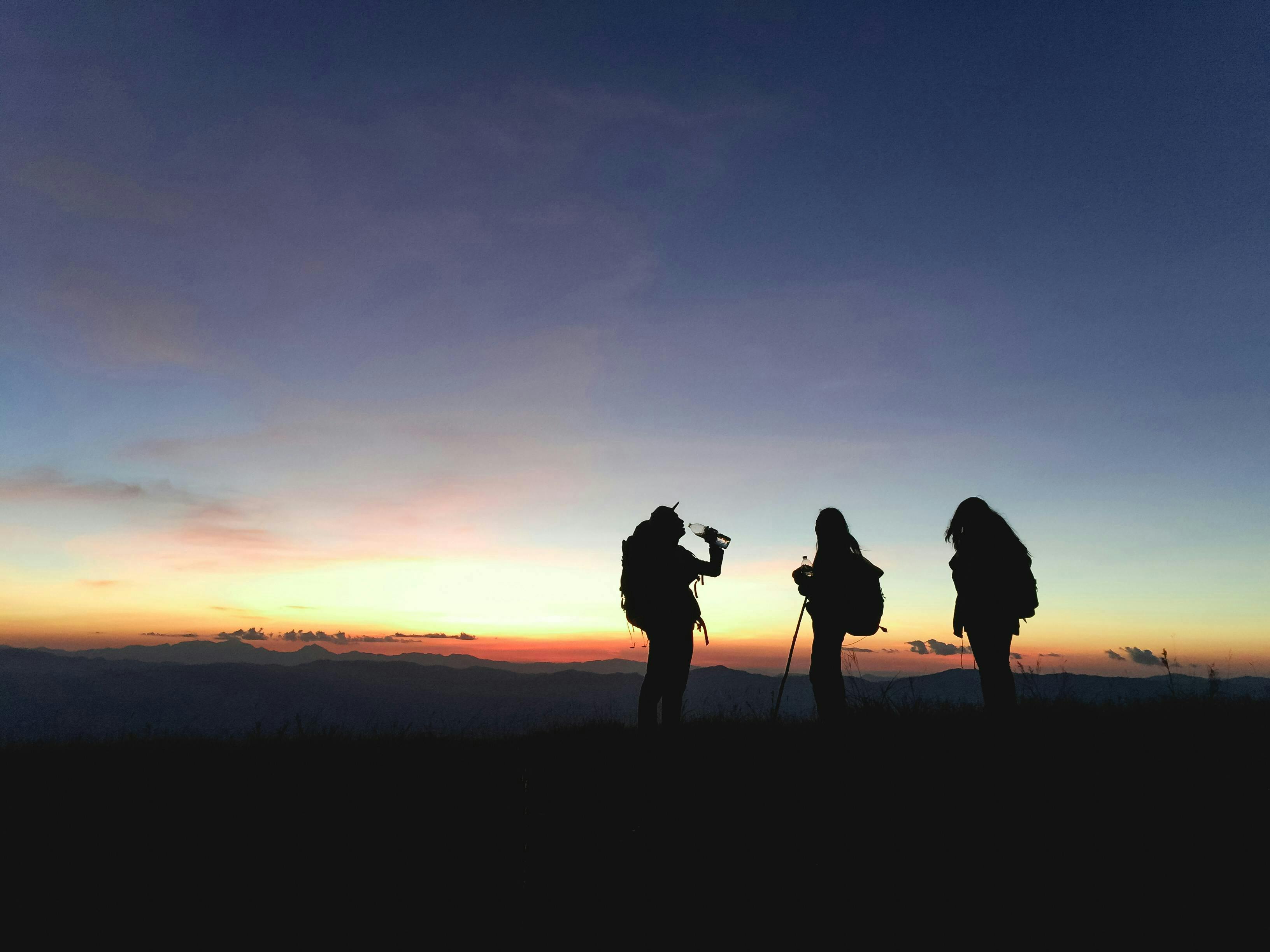 Trois randonneurs face à une fin de coucher de soleil