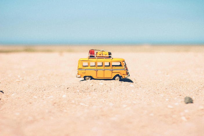 Jouet van jaune posé sur le sable face à la mer