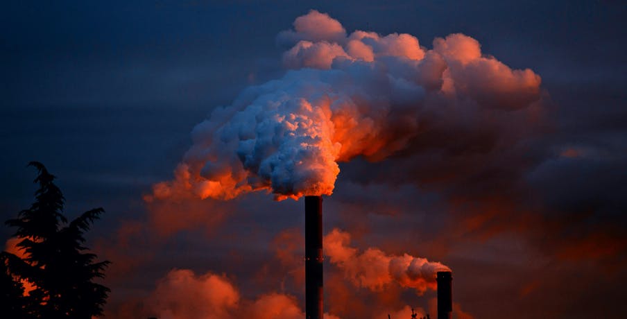 Cheminée d'une usine crachant de la fumée à la tombée de la nuit