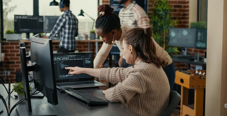 people looking at desktop together at office desk