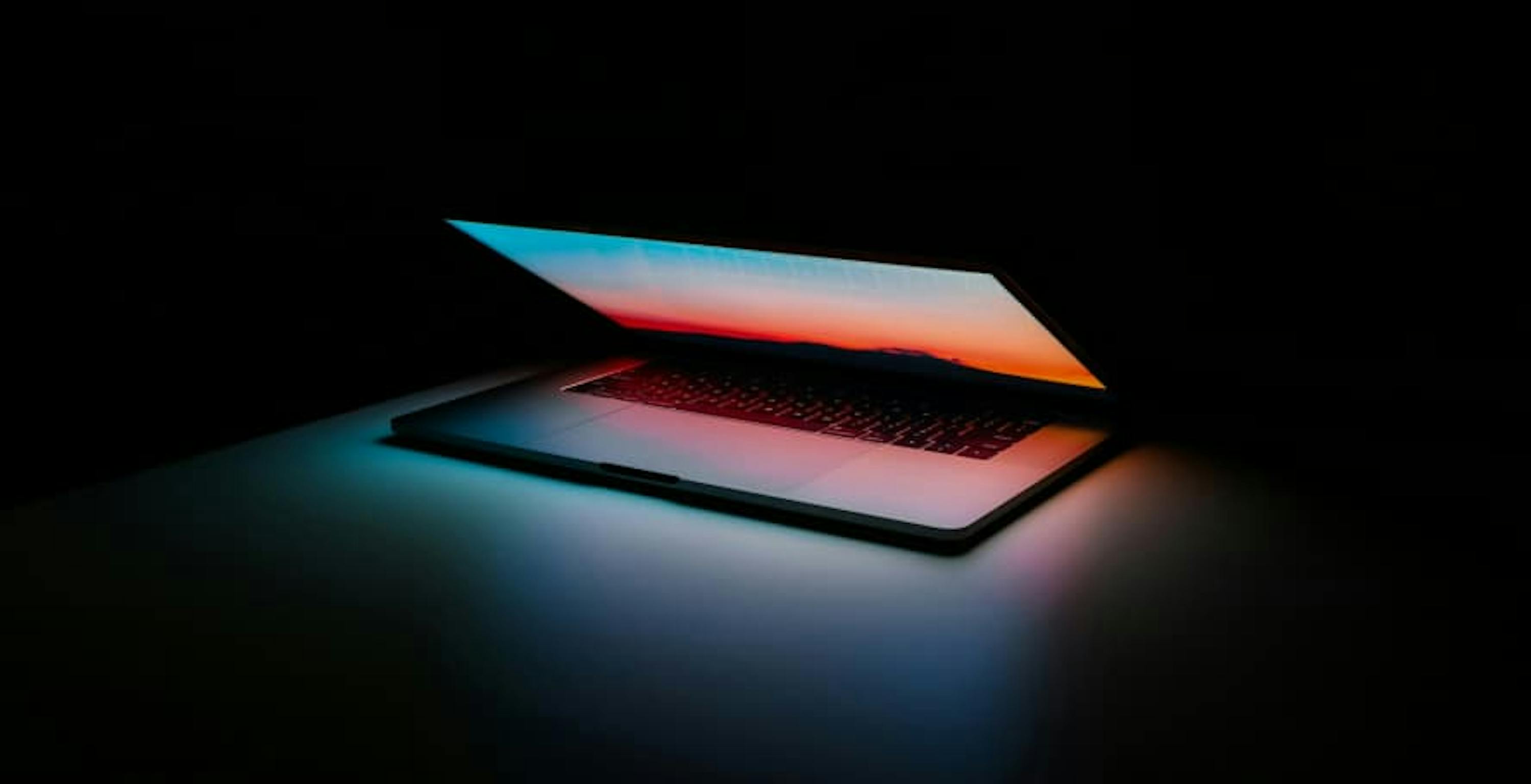 laptop glowing in dark pink/blue