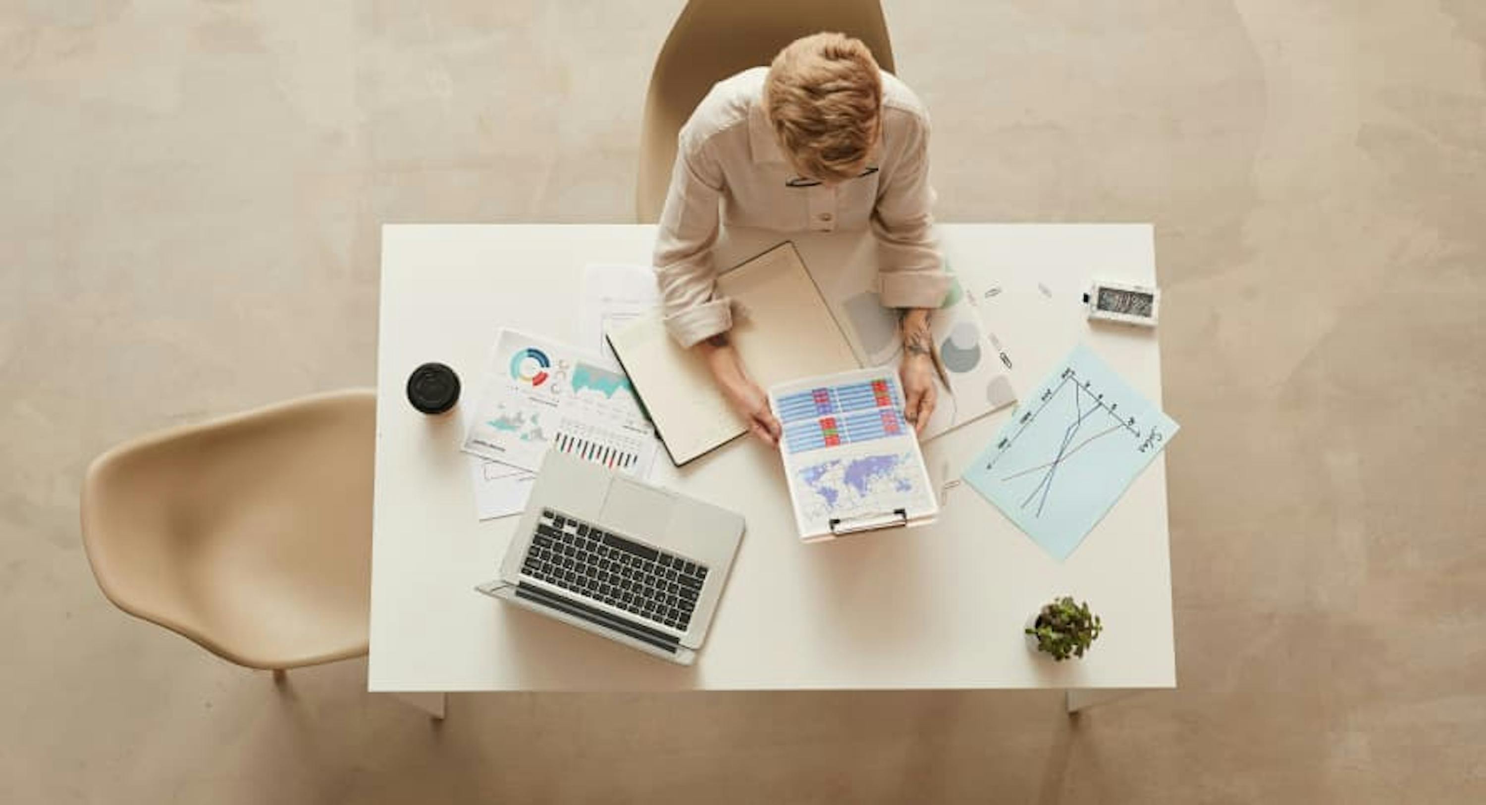 person on laptop from bird's eye view reading graphs with open laptop