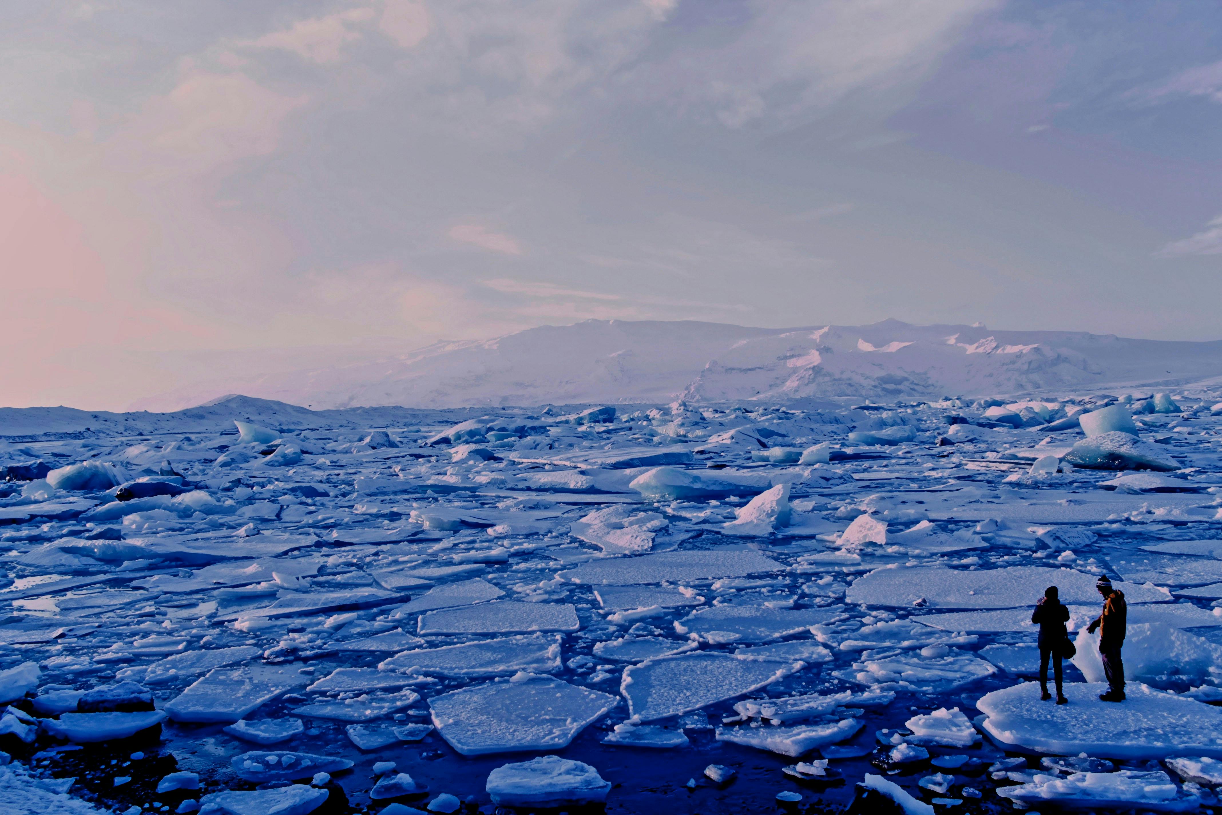 Two people in front of pieces of ice melted in the Ocean