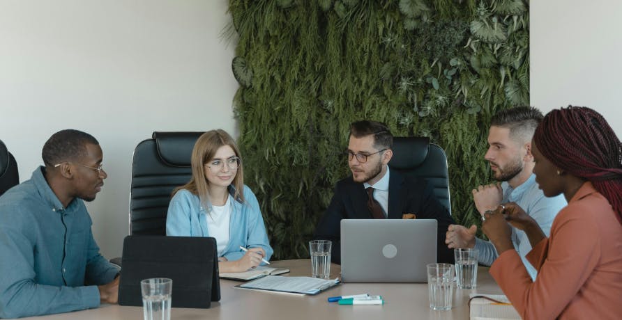 groupe de travail autour d'un bureau avec un mur végétal derrière