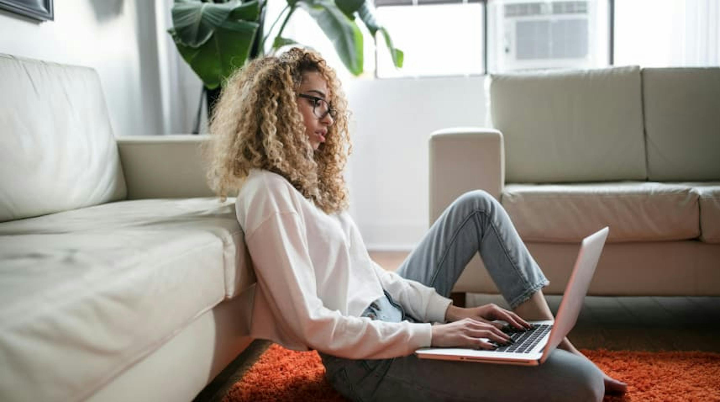 girl on laptop on floor leaning on couch