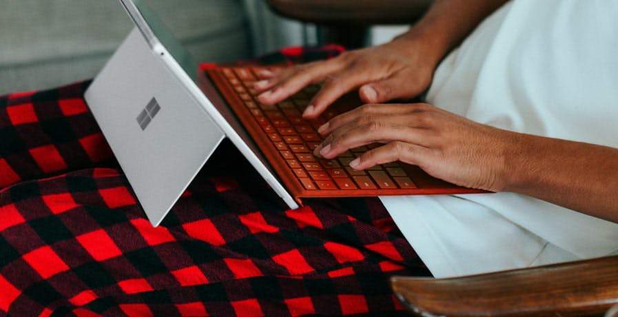 guy in bed with red checkered pajamas with microsoft tablet