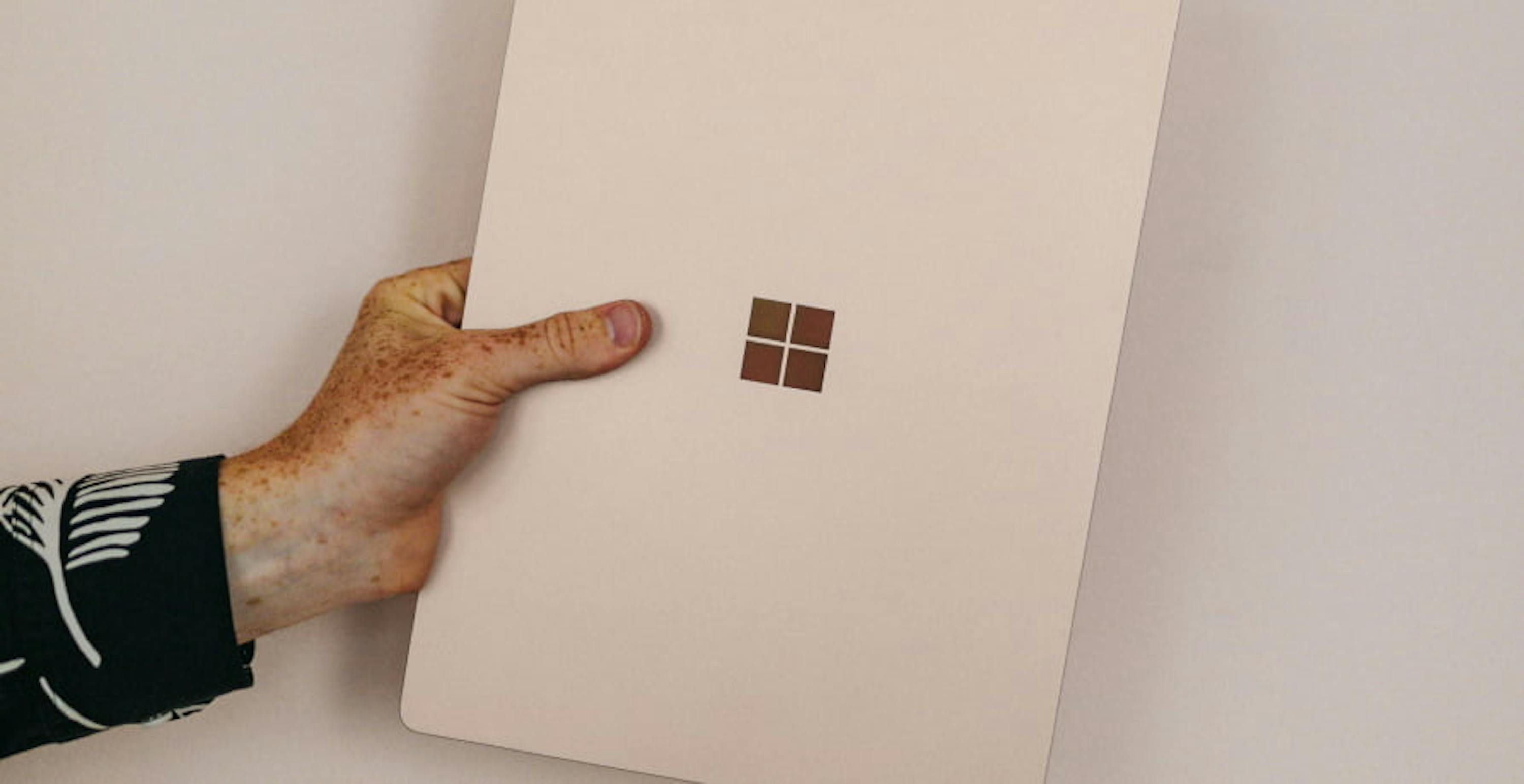 person holding a rose gold microsoft laptop