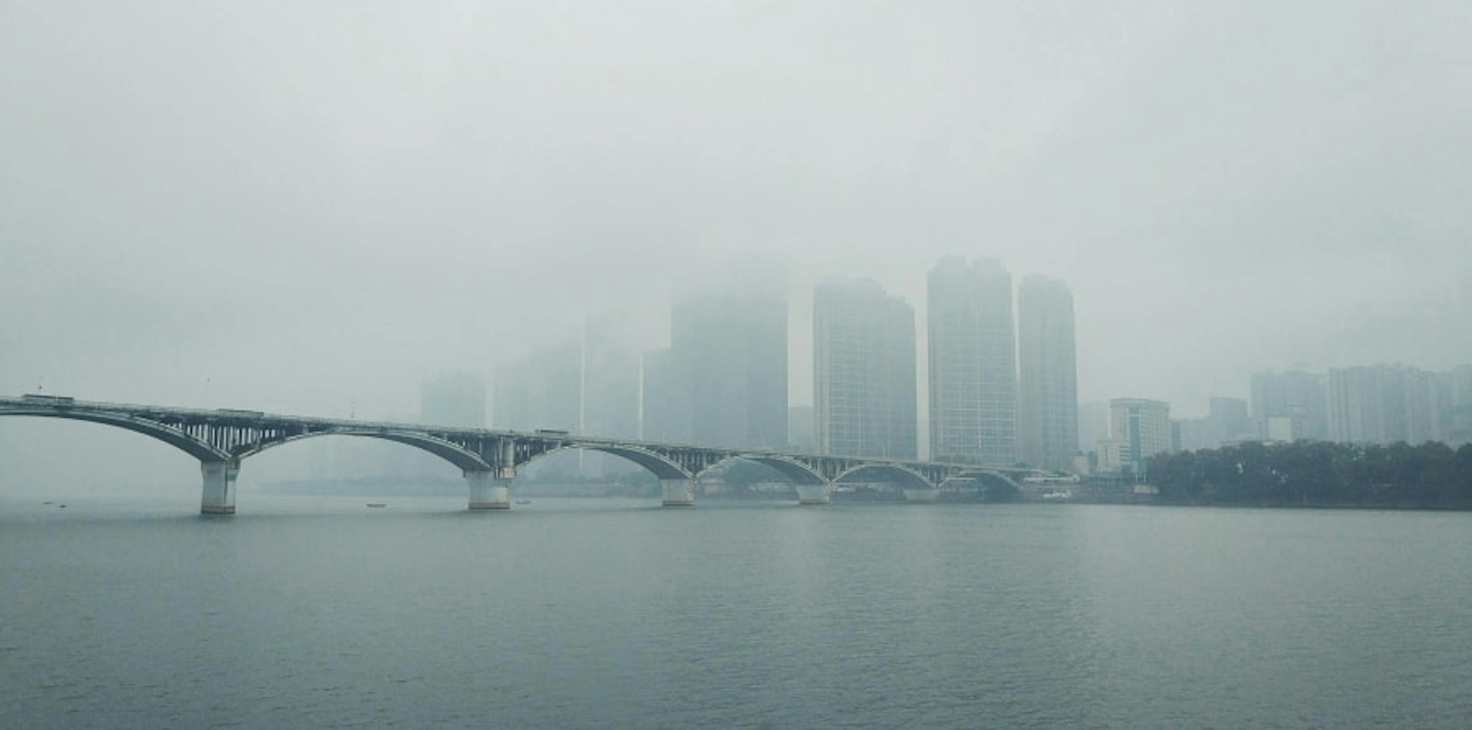 smoggy city with view of bridge over water