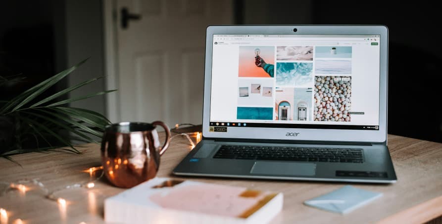 laptop at desk with book