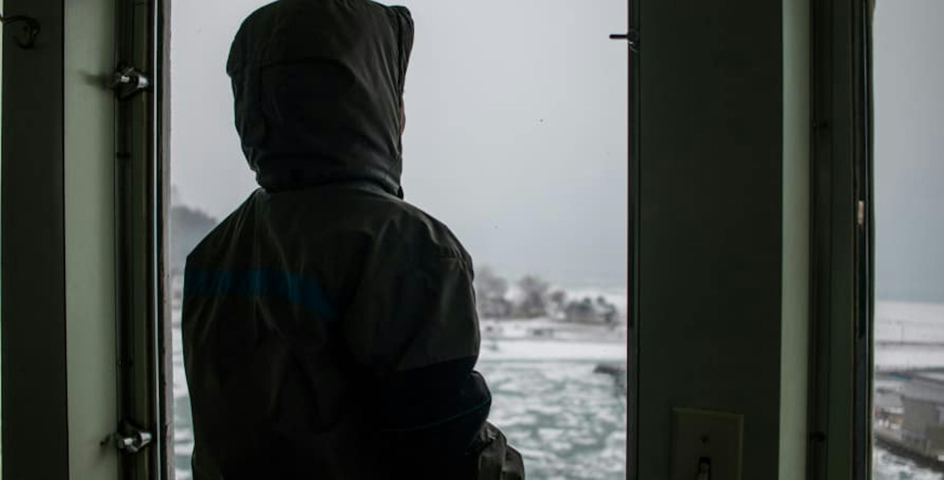 person in jacket overlooking snowy landscape