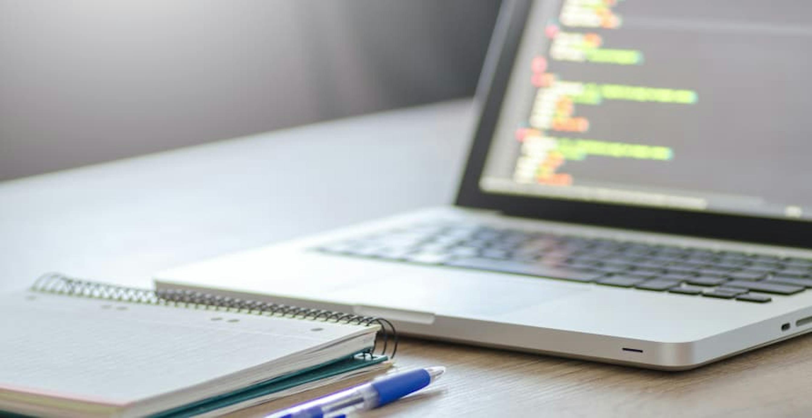 laptop with data open and notepad and pen