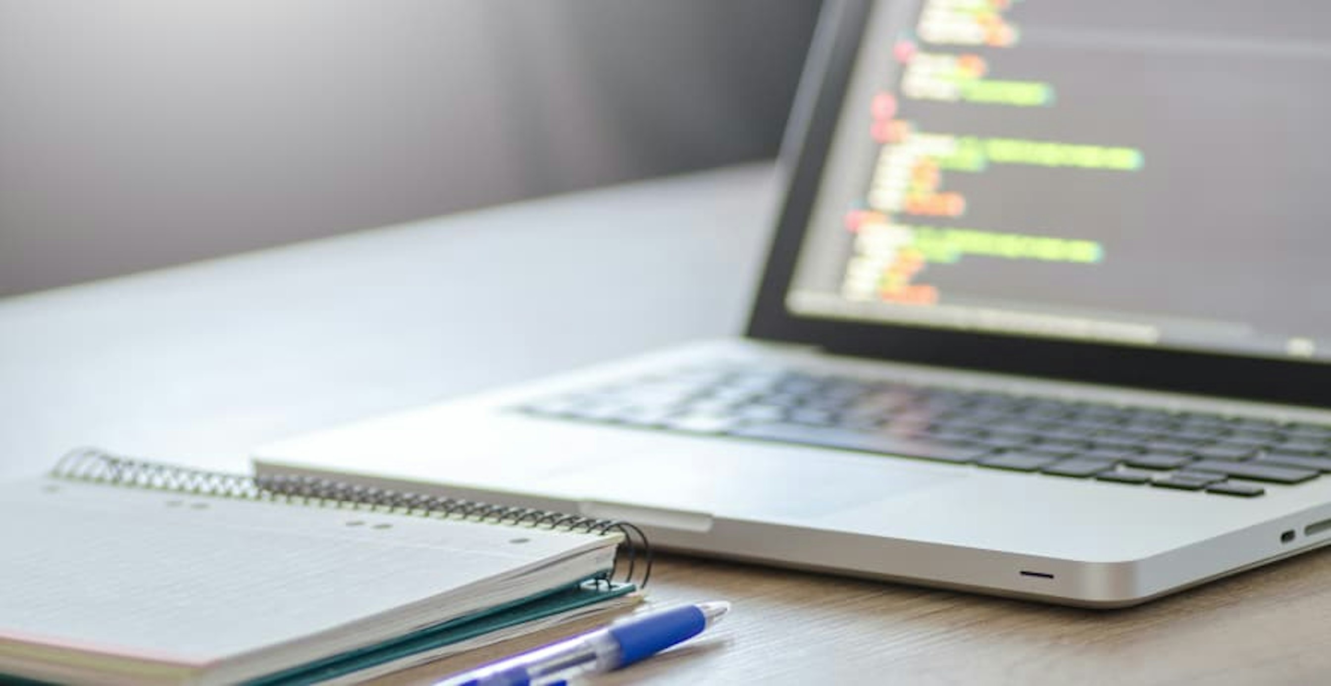 laptop with data open and notepad and pen