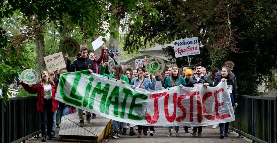 climate change protestors holding up a banner that says climate justice