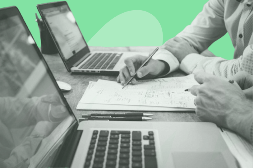 Personne travaillant sur une feuille de papier avec deux ordinateurs portable devant eux
