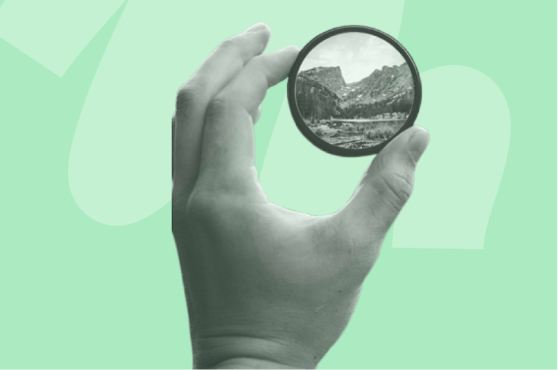 person looking at scenic view through a magnifying glass