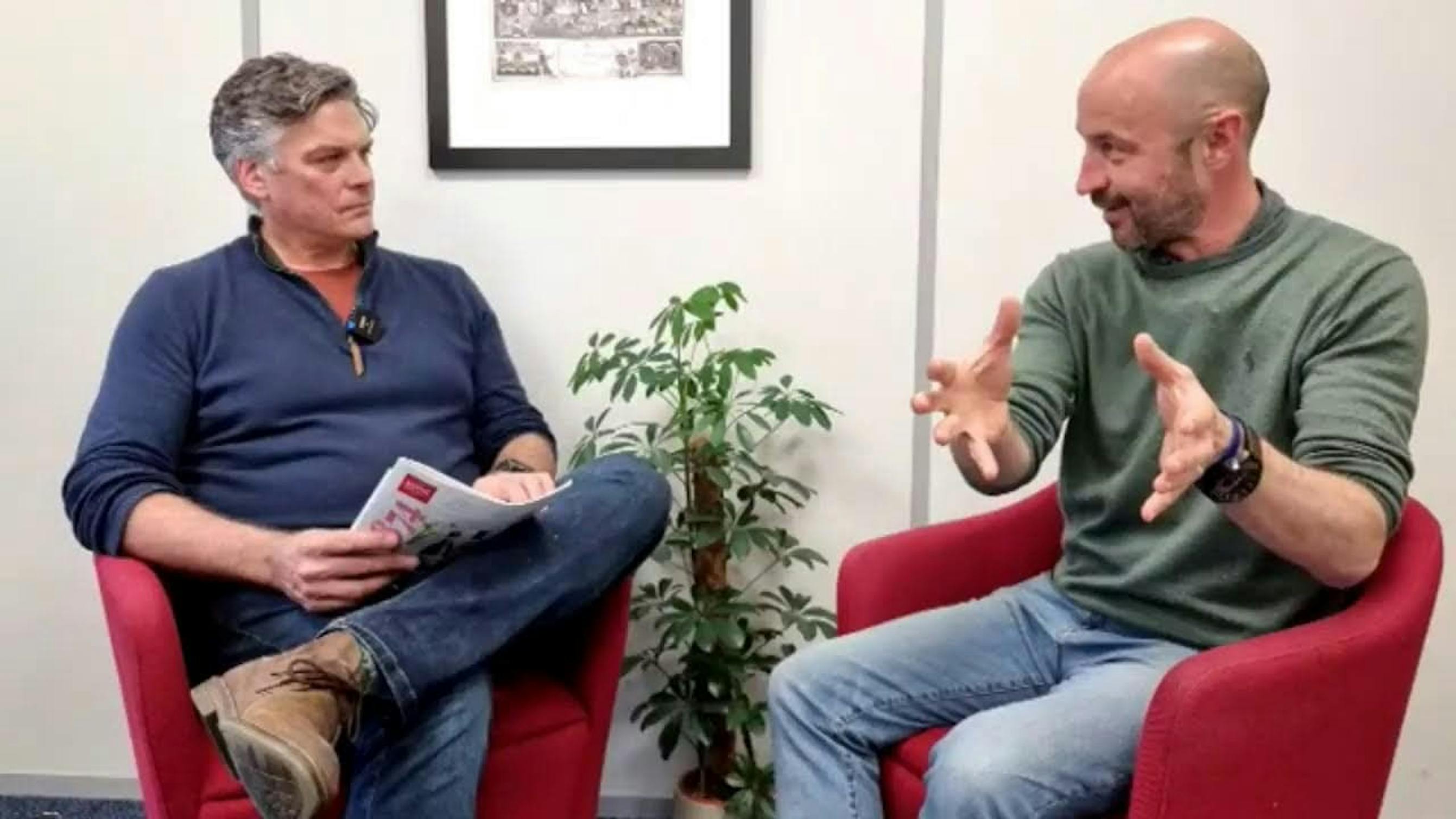 two men on red chairs talking