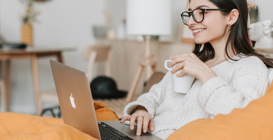 woman working on her laptop while sitting on her couch in the living room