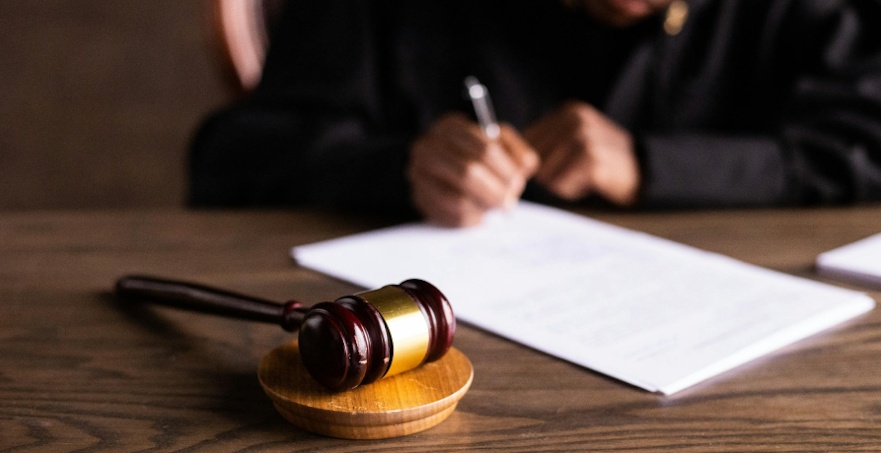 judge writing on legal document with gavel next to him