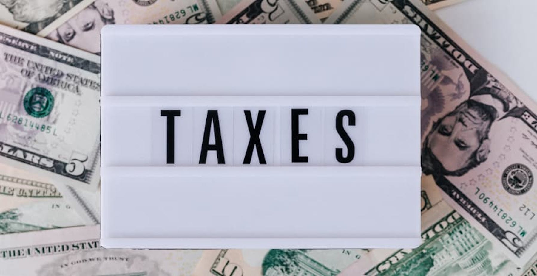 sign that says taxes over usd bills