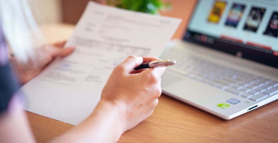 person doing paperwork with laptop in front of them